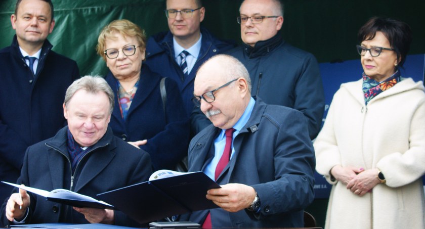 Zdjęcie: Prezes PKP PLK Ireneusz Merchel oraz marszałek Dolnego Śląska Cezary Przybylski podpisują umowy. Stoją dolnośląski radny Piotr Karwan, posłanka Ewa Szymańska, wiceminister infrastruktury Andrzej Bittel, senator Krzysztof Mróz i marszałek Sejmu Elżbieta Witek.